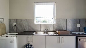 Una cocina con un lavabo doble, una ventana sobre el lavabo y una lavadora.