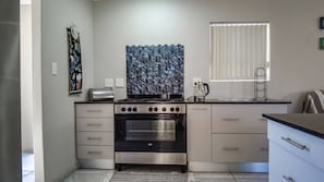 Eine kleine Küche mit Backofen, Toaster und einem Fenster mit Jalousien.