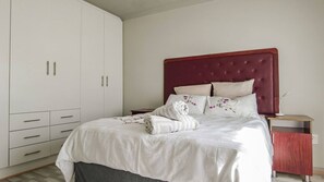 Un dormitorio con cama, mesita de noche, armario y escritorio.