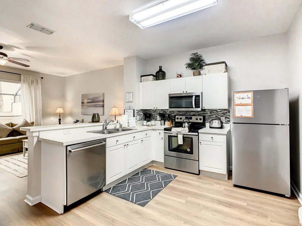 Een moderne keuken met witte kasten, roestvrijstalen apparatuur en een backsplash met een herringbone patroon.