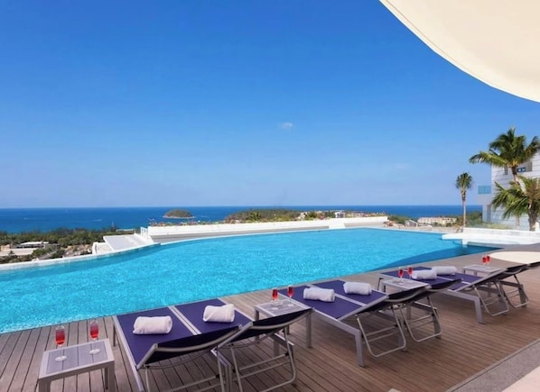 Ein Poolbereich mit Liegestühlen und Blick auf das Meer.