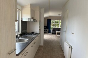 Une cuisine moderne équipée d’une cuisinière à gaz, d’un évier double et offrant une vue sur un espace de vie comprenant un canapé et une table.