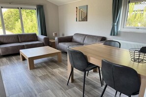 A modern living room with a sofa, a dining table, and chairs. - Charming cottage with sauna on the island of Texel (Den Burg)