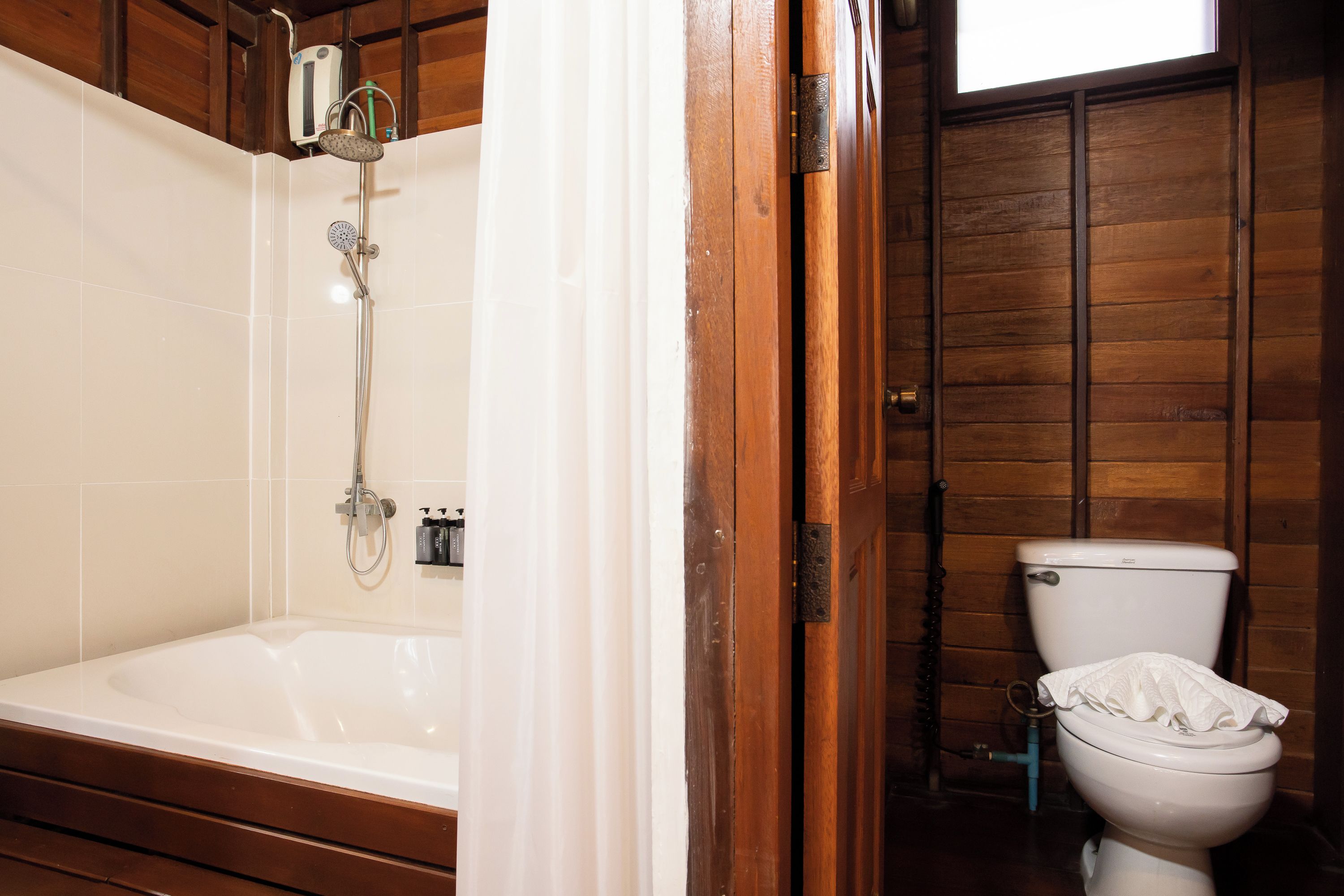 A bathroom with a bathtub, toilet, and wooden walls.