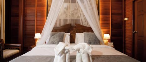 A hotel room with a four-poster bed, two bedside lamps, and a wooden wall.