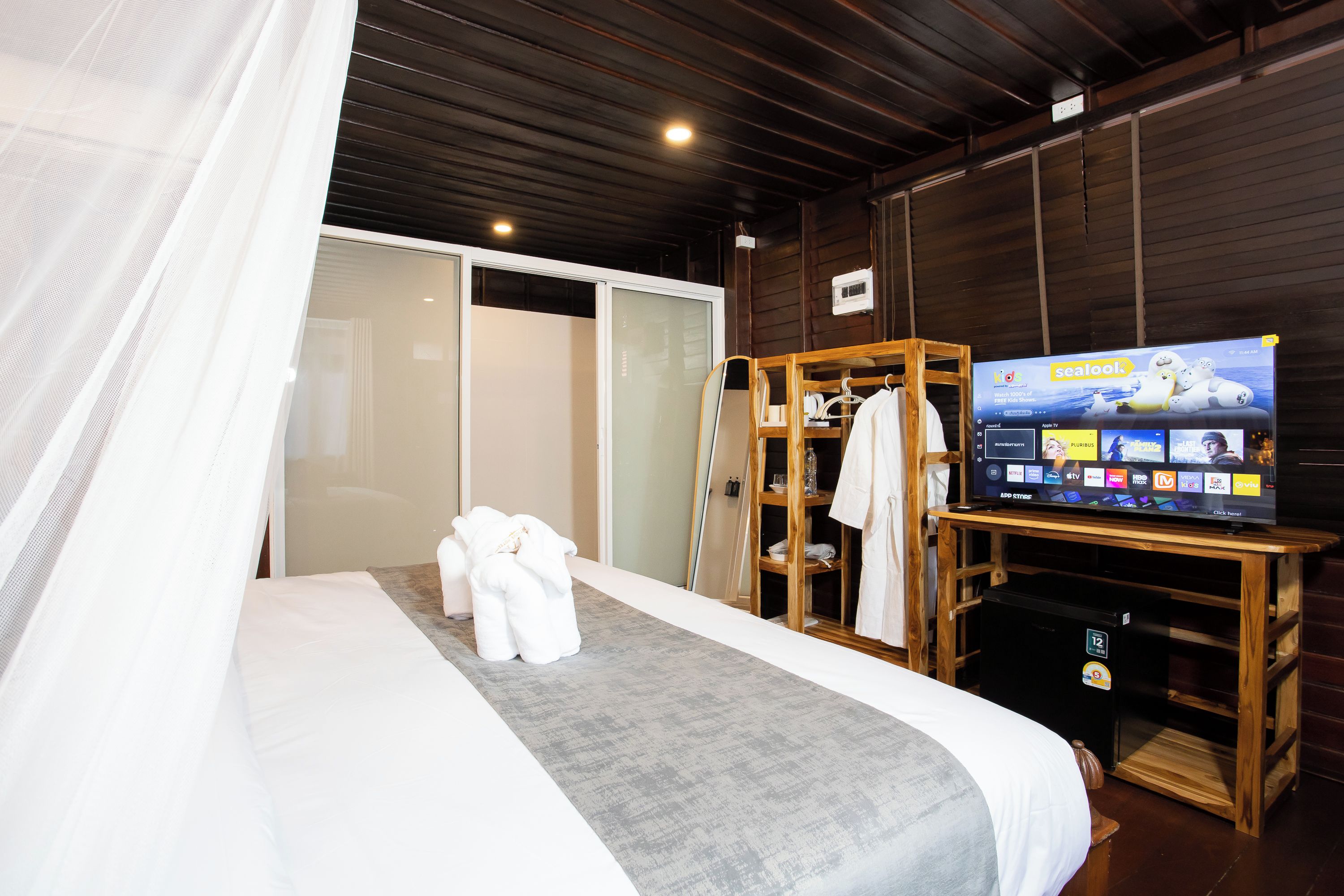 Ein Hotelzimmer mit einem Bett, einem Fernseher, einem Holzschrank und einem weißen Bademantel.