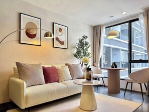 Ein modernes Wohnzimmer mit einer Couch, einem Couchtisch und Blick auf ein Gebäude durch große Fenster.