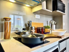 Eine moderne Küche mit Edelstahlgeräten, einem Glasbehälter mit Pasta und einem Holzer Schneidebrett.