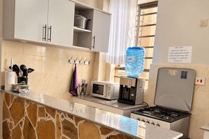 A modern kitchen with a gas stove, a microwave, and a water dispenser. - Likizo Homes - Rehema Apartment, 202, Naivasha (Naivasha)