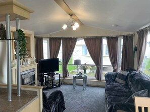 A living room with a fireplace, television, and a sofa. - Lyons Robin Hood - Holiday Accommodation 15838 (Rhyl)