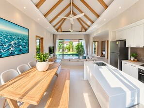 A modern kitchen with white cabinetry, a built-in island, and a ceiling fan. - Brand New Private 3-Bedroom Pool Villa in Bang Tao, Phuket (Thep Krasatti)