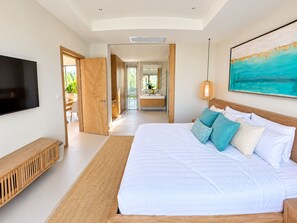 A modern bedroom with a large bed, a TV, and a painting on the wall. - Brand New Private 3-Bedroom Pool Villa in Bang Tao, Phuket (Thep Krasatti)
