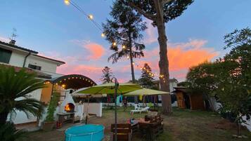 A backyard with a barbecue grill, a swimming pool, and string lights.