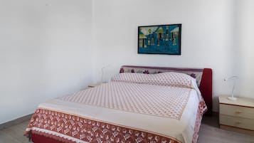 A bedroom with a bed, a nightstand, a lamp, and a wall-mounted painting.