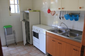 Una cocina con armarios blancos, un fregadero de acero inoxidable y una estufa blanca.