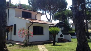 A two-story house with a tiled roof, a small garden with a palm tree, and a satellite dish on the roof.