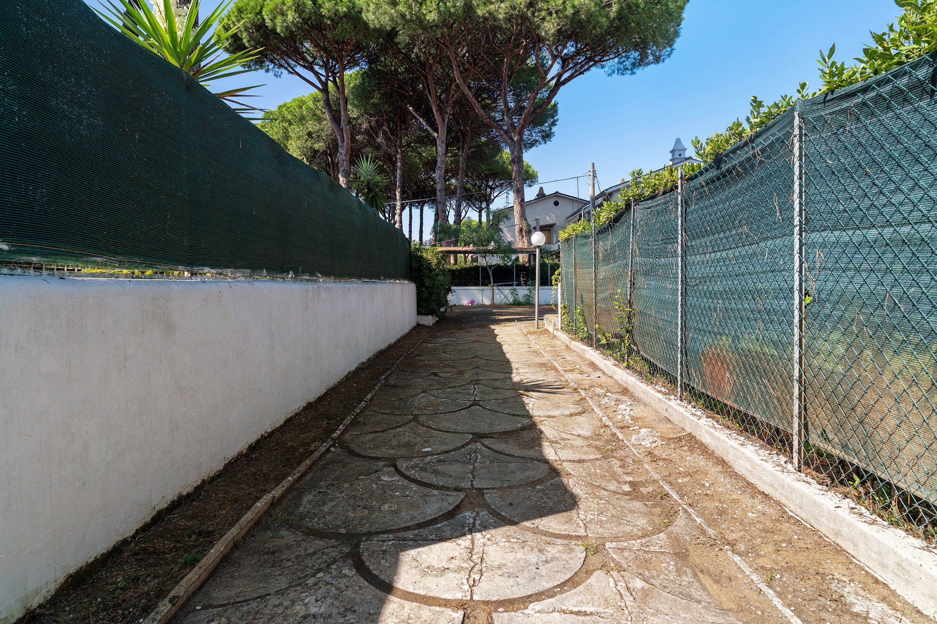 Un estrecho sendero con pavimento decorativo que lleva a una zona residencial.