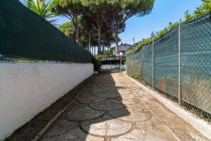 A narrow pathway with patterned paving leading to a residential area.