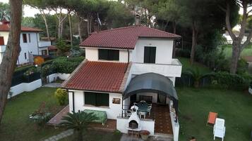 Ein zweistöckiges Haus mit rotem Ziegeldach, einer Terrasse mit Gartenmöbeln und einem kleinen Garten.