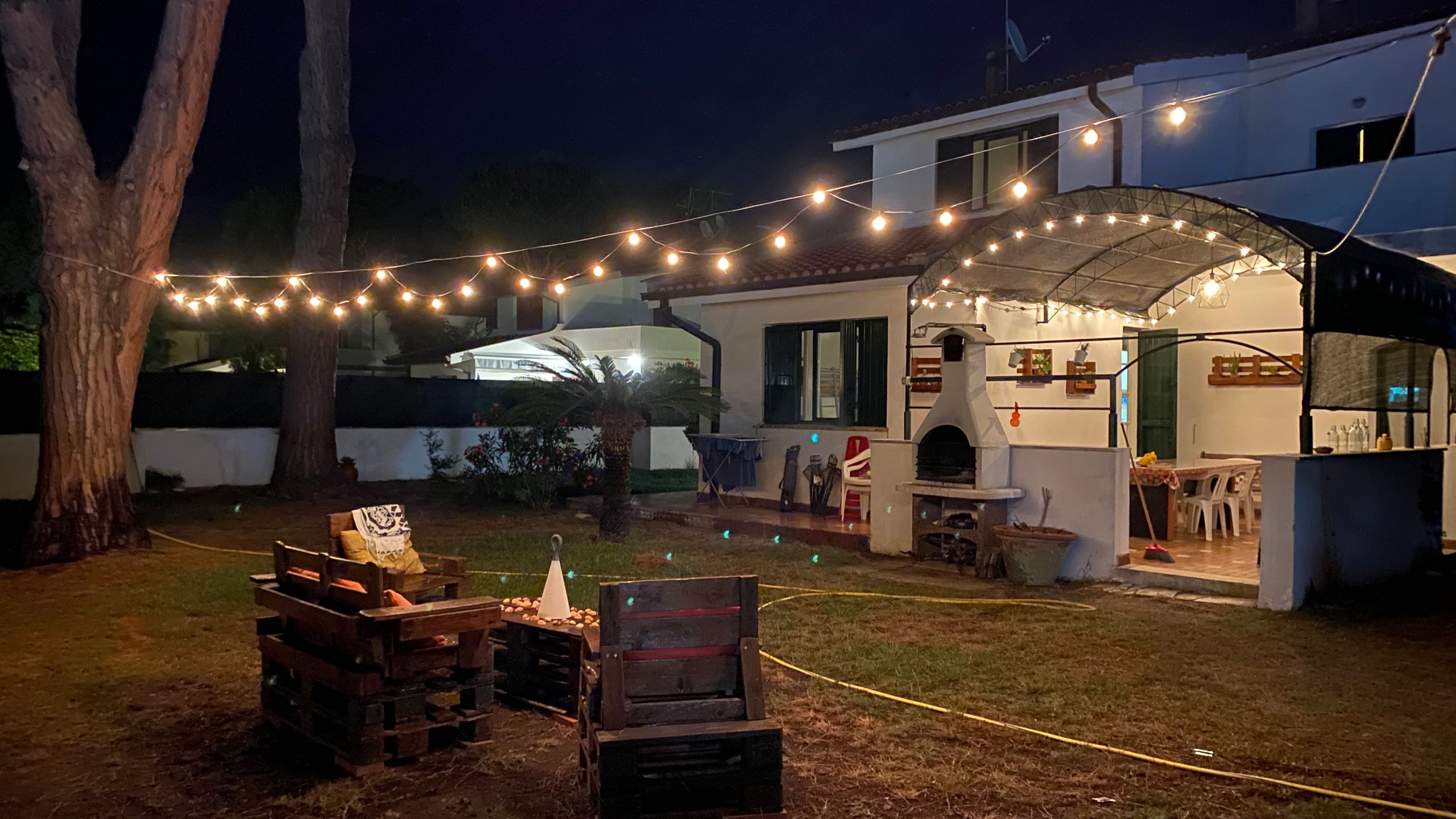 A backyard with a barbecue area, outdoor seating, and string lights.