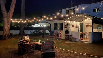 A backyard with a barbecue area, outdoor seating, and string lights.