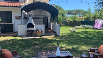 Un giardino attrezzato con forno a mattoni, posti a sedere all'aperto e luci decorative appese.