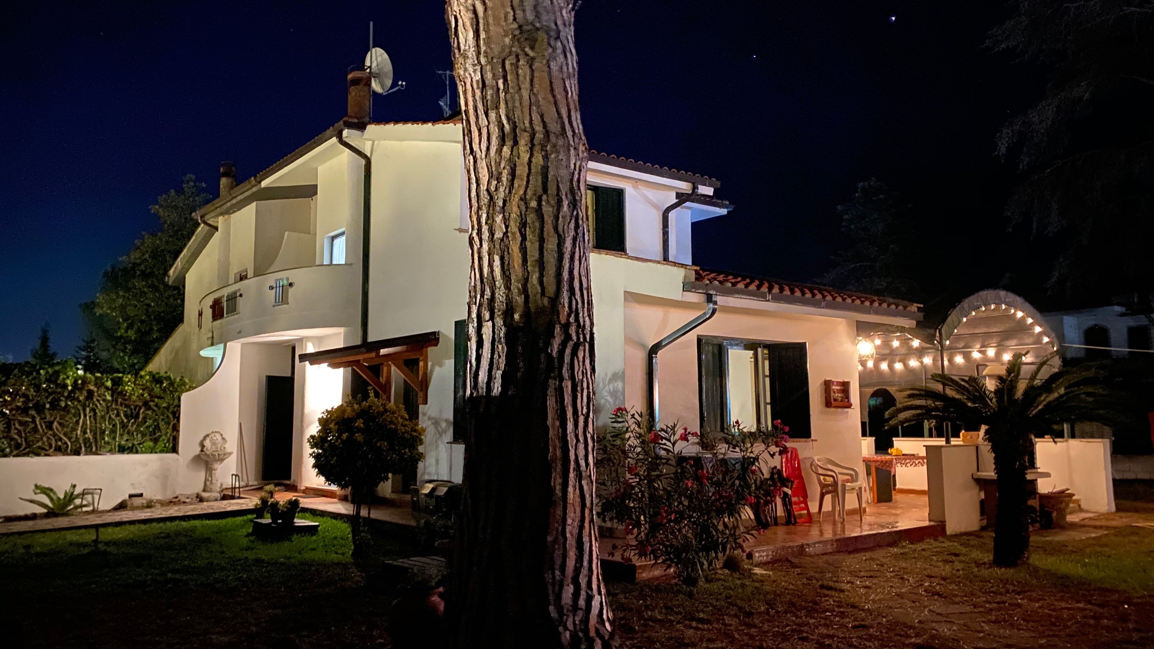 A two-story house with a garden, a satellite dish, and outdoor lighting.