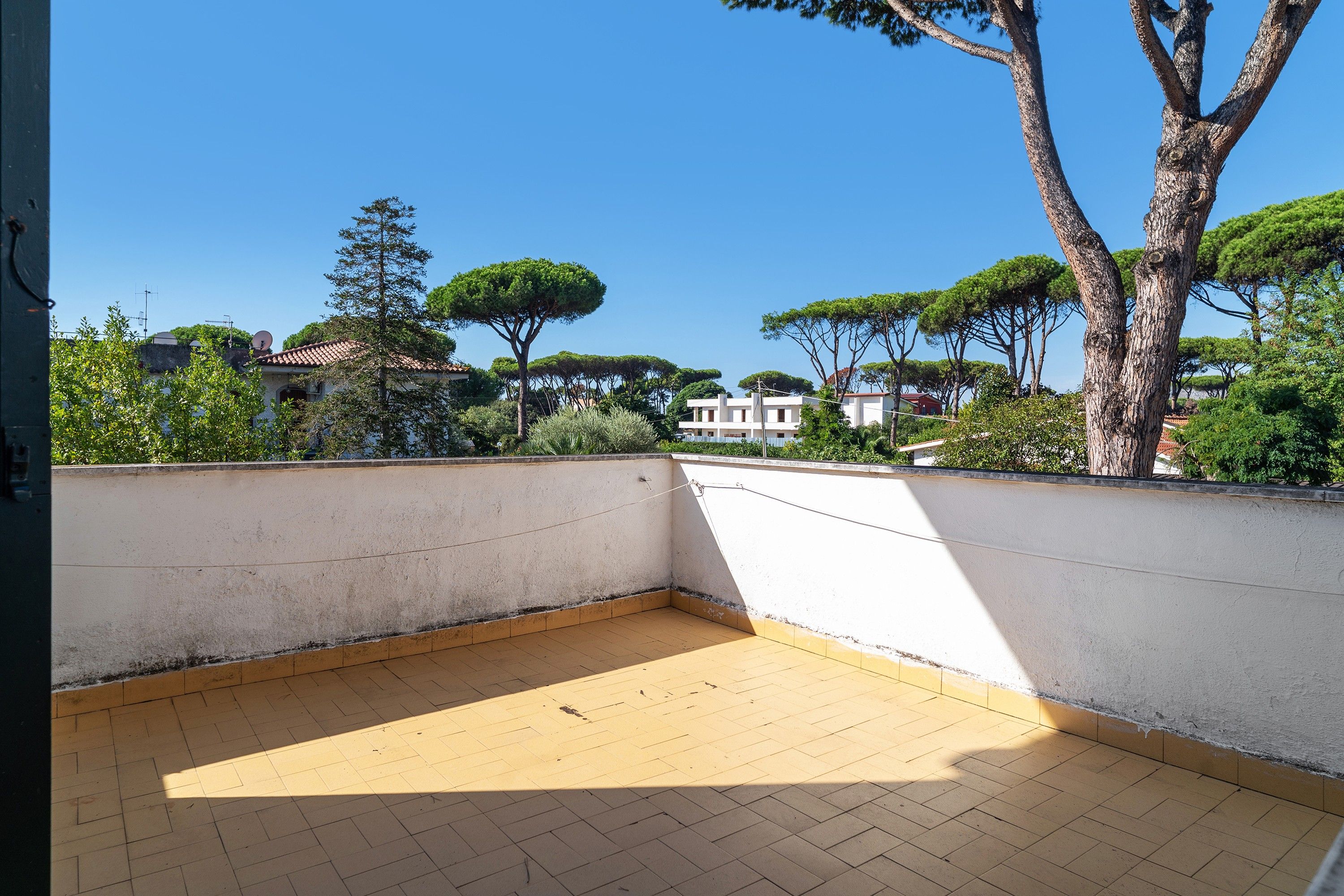 An empty balcony with a tiled floor and a white wall.