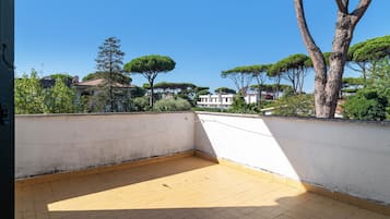An empty balcony with a tiled floor and a white wall.