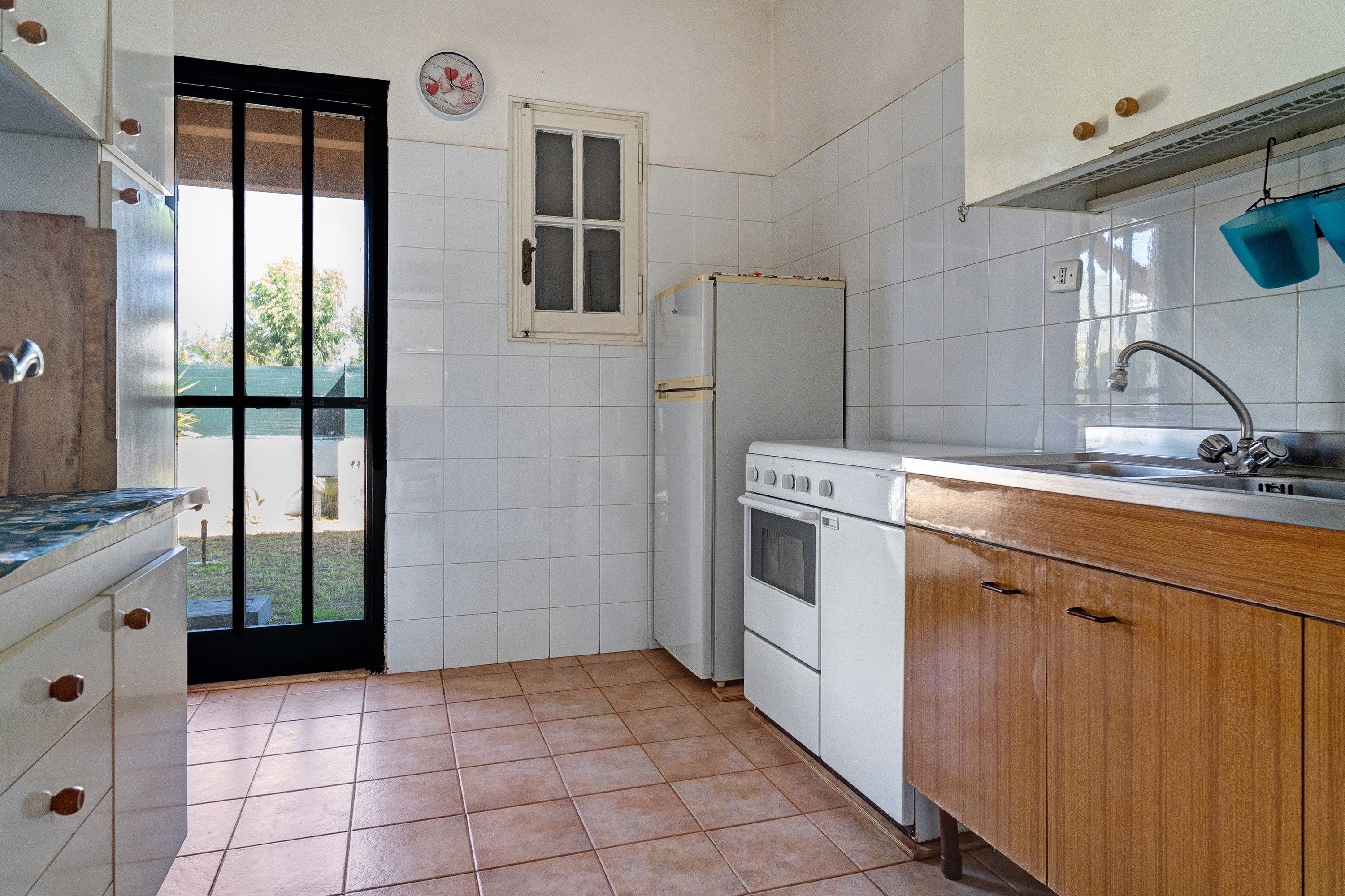 Een kleine keuken met een koelkast, oven en wastafel.