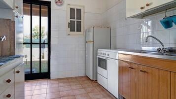 Een kleine keuken met een koelkast, oven en wastafel.