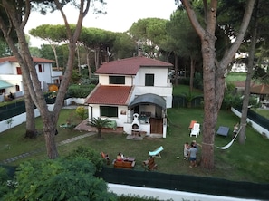 Una casa de dos pisos con un patio rodeado de árboles.