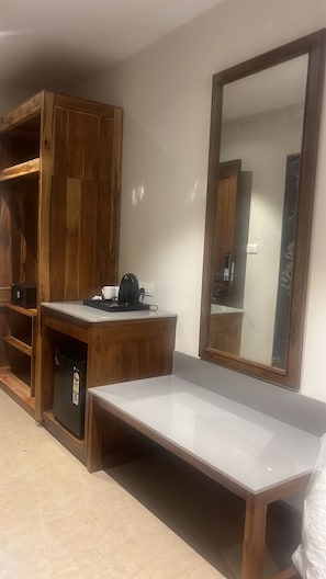 Una pequeña kitchenette equipada con refrigerador, cafetera y microondas.