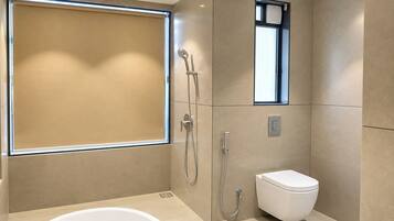 A modern bathroom with a bathtub, a shower, and a toilet.