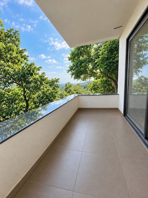 Un balcón con vista despejada a árboles y un paisaje lejano.