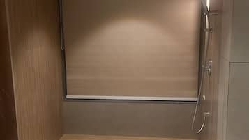 A bathroom with a shower, a wooden door, and a tiled floor.