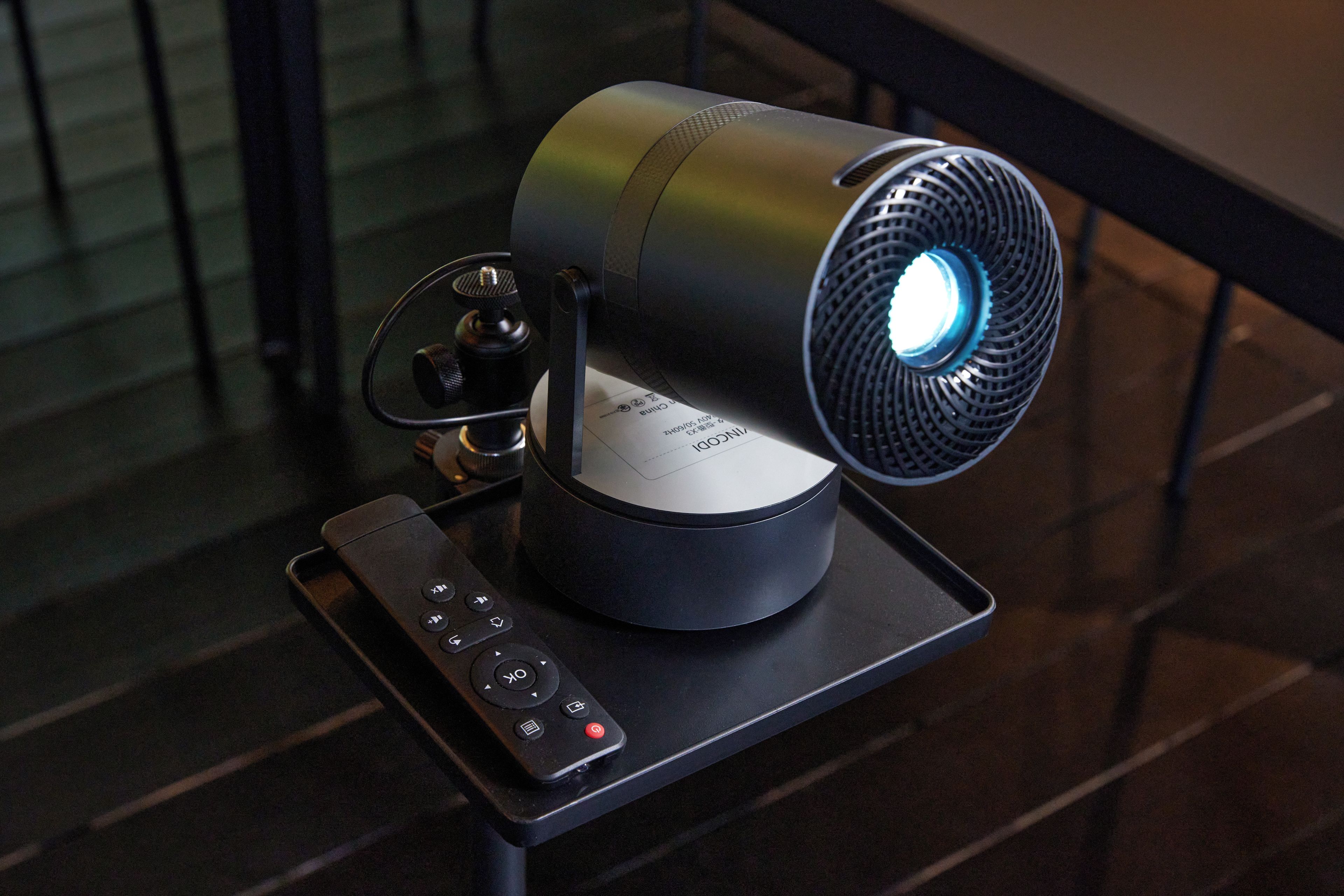 A projector with a remote control on a stand.