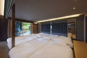 Une chambre d’hôtel moderne dotée d  ’un grand lit, offrant une vue sur l’extérieur et donnant sur un balcon par le biais d’une porte coulissante.
