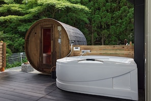 A hot tub on a wooden deck with a wooden sauna door in the background.