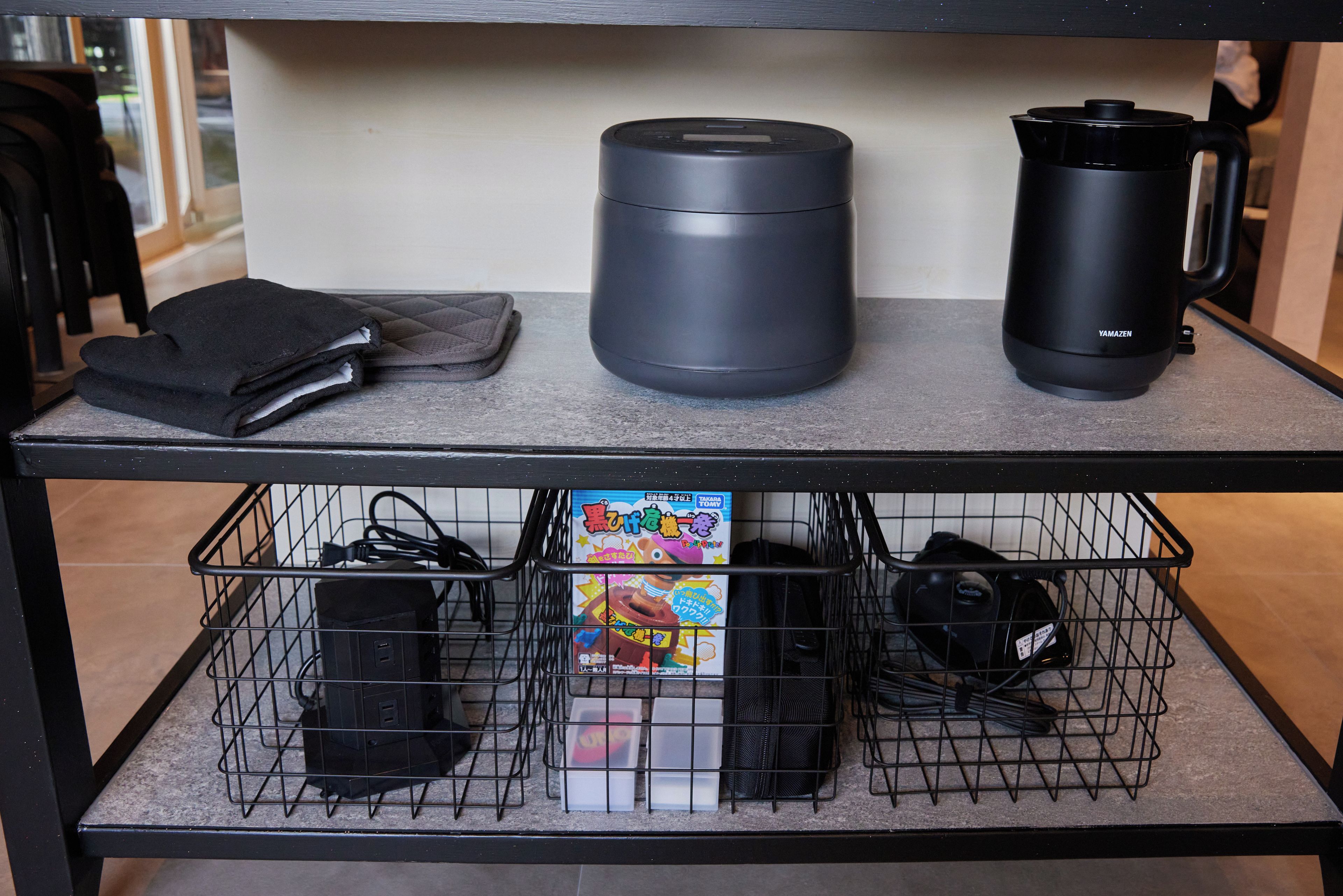 A kitchen counter with a coffee maker, a kettle, and a power strip with cords.