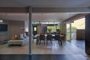 Un interior moderno con comedor, sofá y cocina visible a través de una puerta abierta.