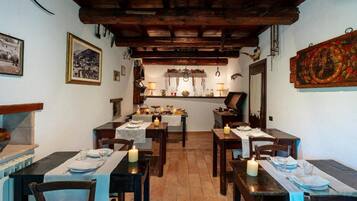 Un comedor con mesas y sillas de madera, y un ambiente iluminado por velas.