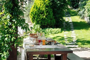 An outdoor dining table set with glassware, plates, and a basket, surrounded by greenery and a stone pathway. - ROMITO - Relais & Spa (FIUME)