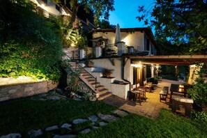 A house with a stone staircase leading to a balcony, outdoor seating area, and a well-lit patio. - ROMITO - Relais & Spa (FIUME)
