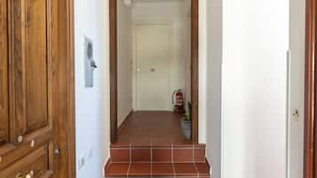 Ein Flur mit einer Holztür, einer gefliesten Treppe und einer weißen Wand.