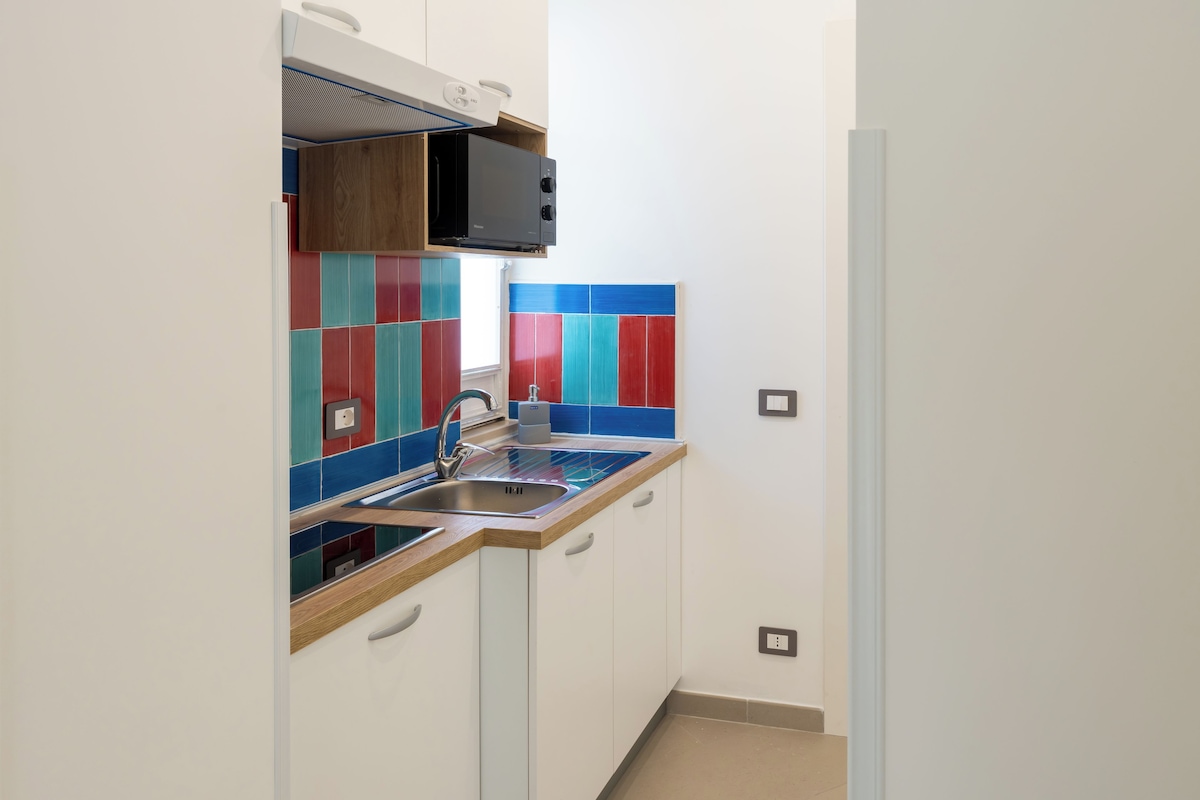 A compact kitchen with a built-in microwave, a sink, and a window.