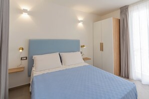 A bedroom with a bed, bedside tables, a wardrobe, and a window with curtains.