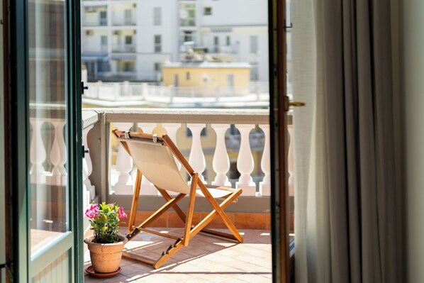 A balcony with a wooden chair and a potted plant.