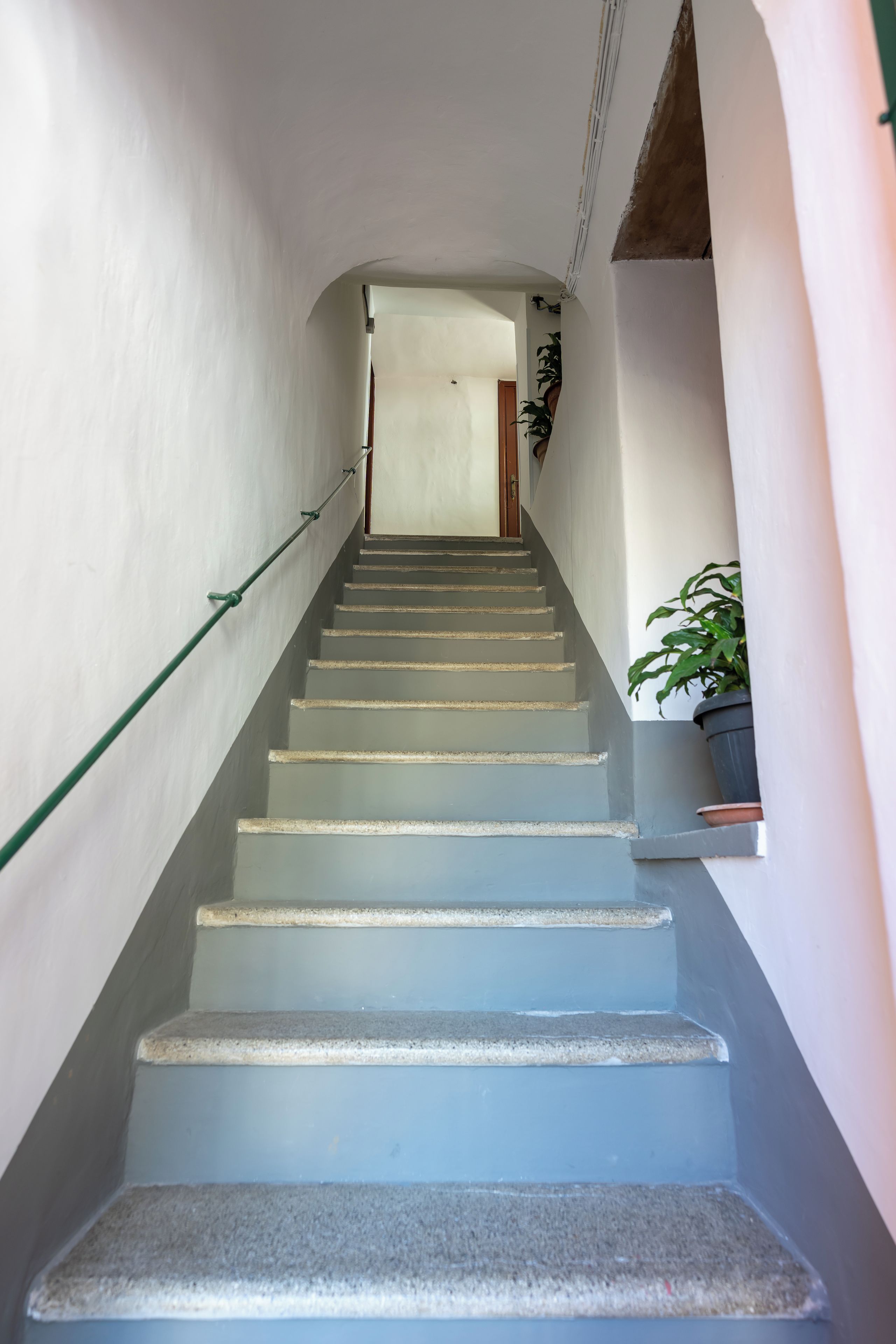A staircase with a handrail, leading to a door at the top.