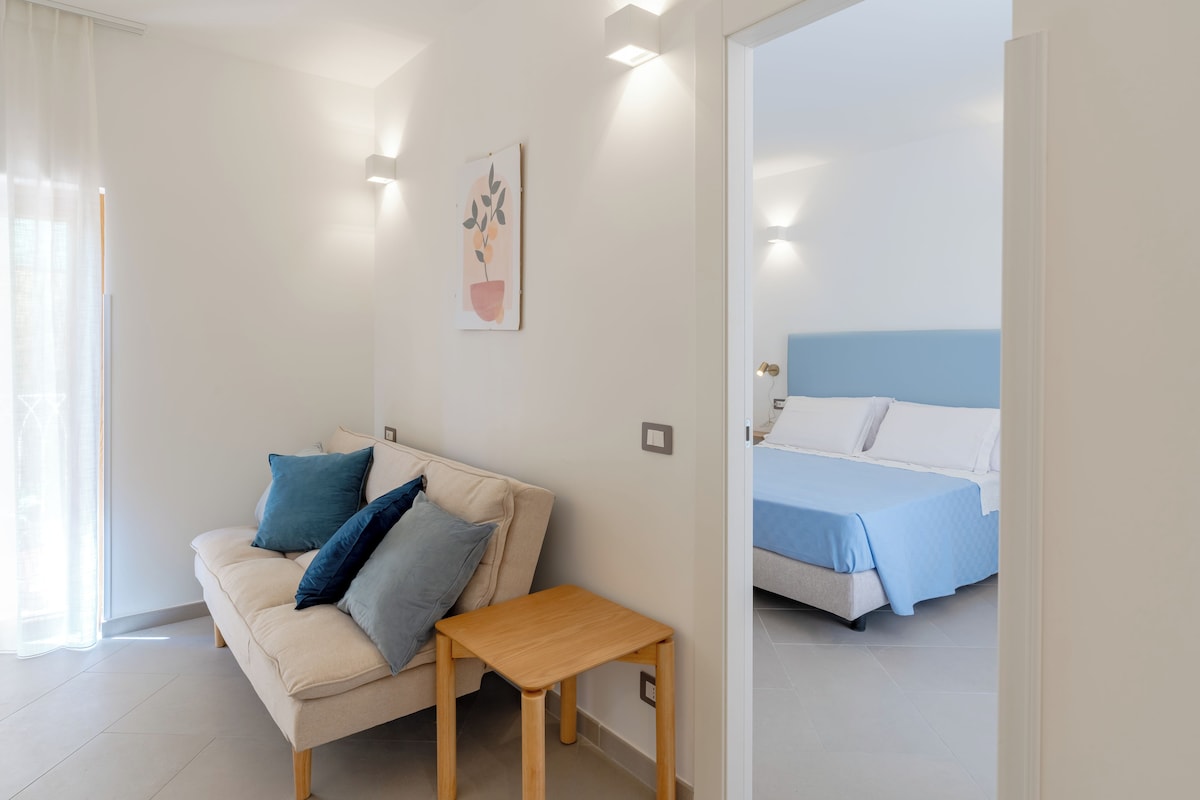 A modern bedroom with a bed, a sofa, and a small table.
